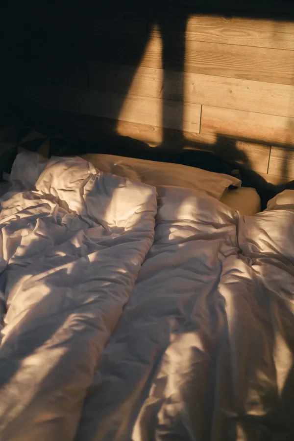 Luz de la mañana entrando en un dormitorio con la cama deshecha